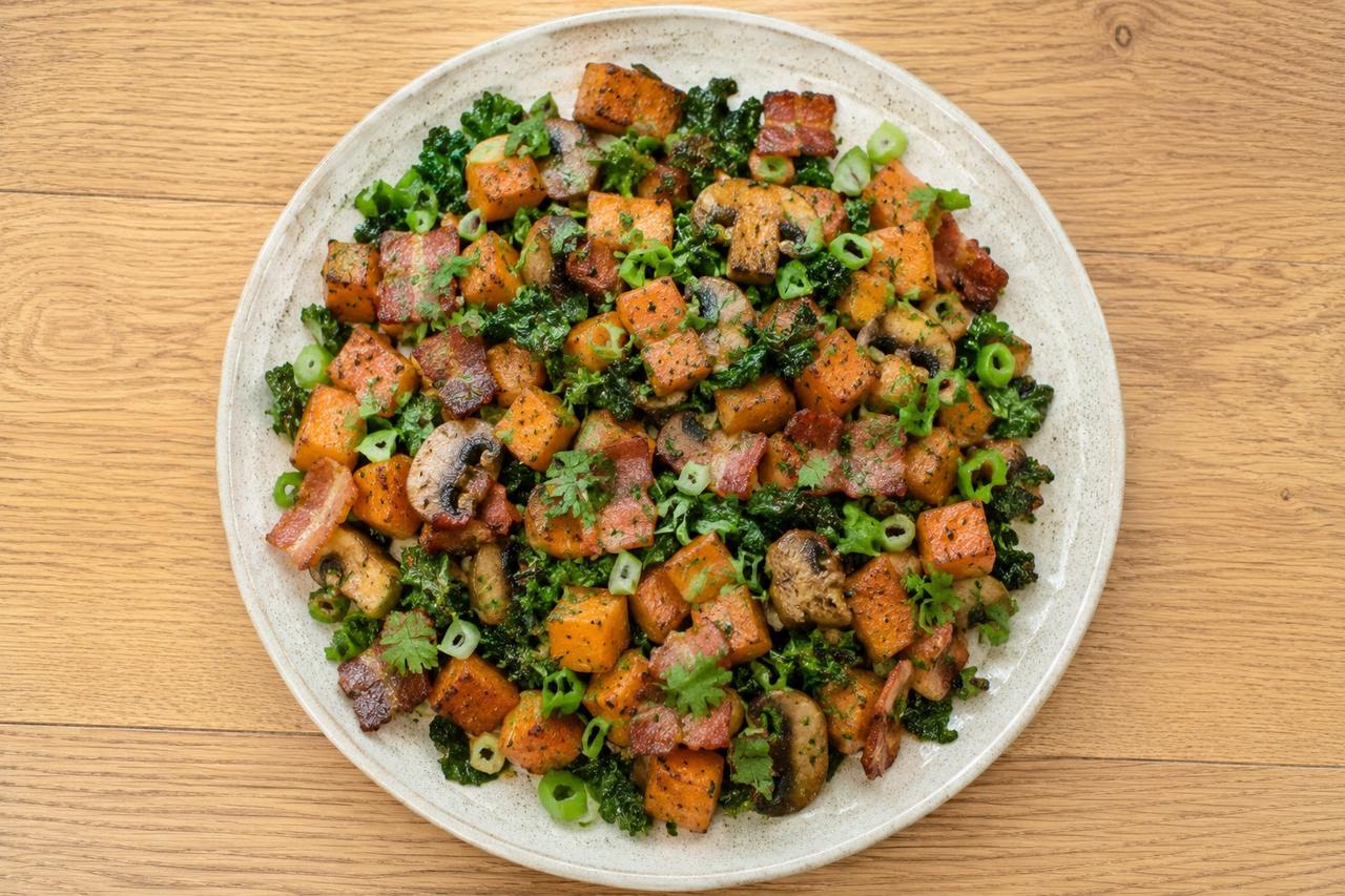 A savory skillet hash of diced Japanese sweet potato caramelized in bacon fat with mushrooms and kale, finished with fresh herbs
